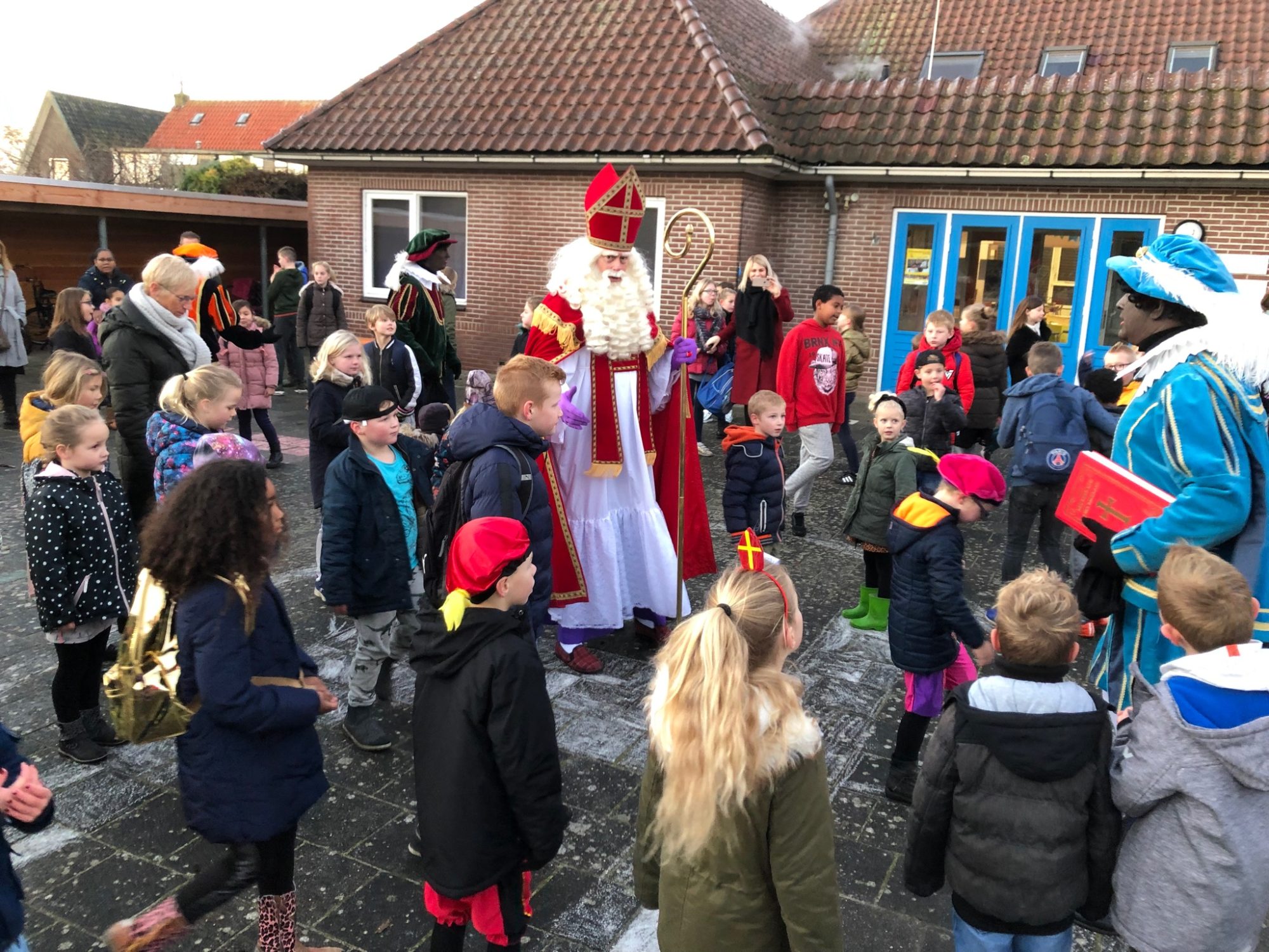 Sinterklaas en de Pieten tussen de kinderen op het schoolplein