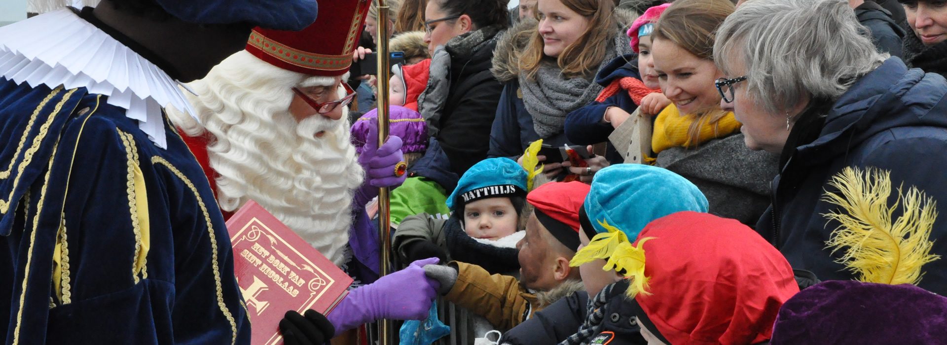 Sinterklaas begroet kinderen in het publiek bij de intocht