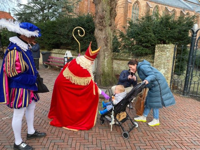 Sinterklaas begroet een kindje in de kinderwagen