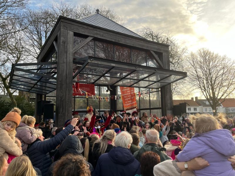 Publiek zwaait naar Sinterklaas en de Pieten bij het paviljoen op het plein